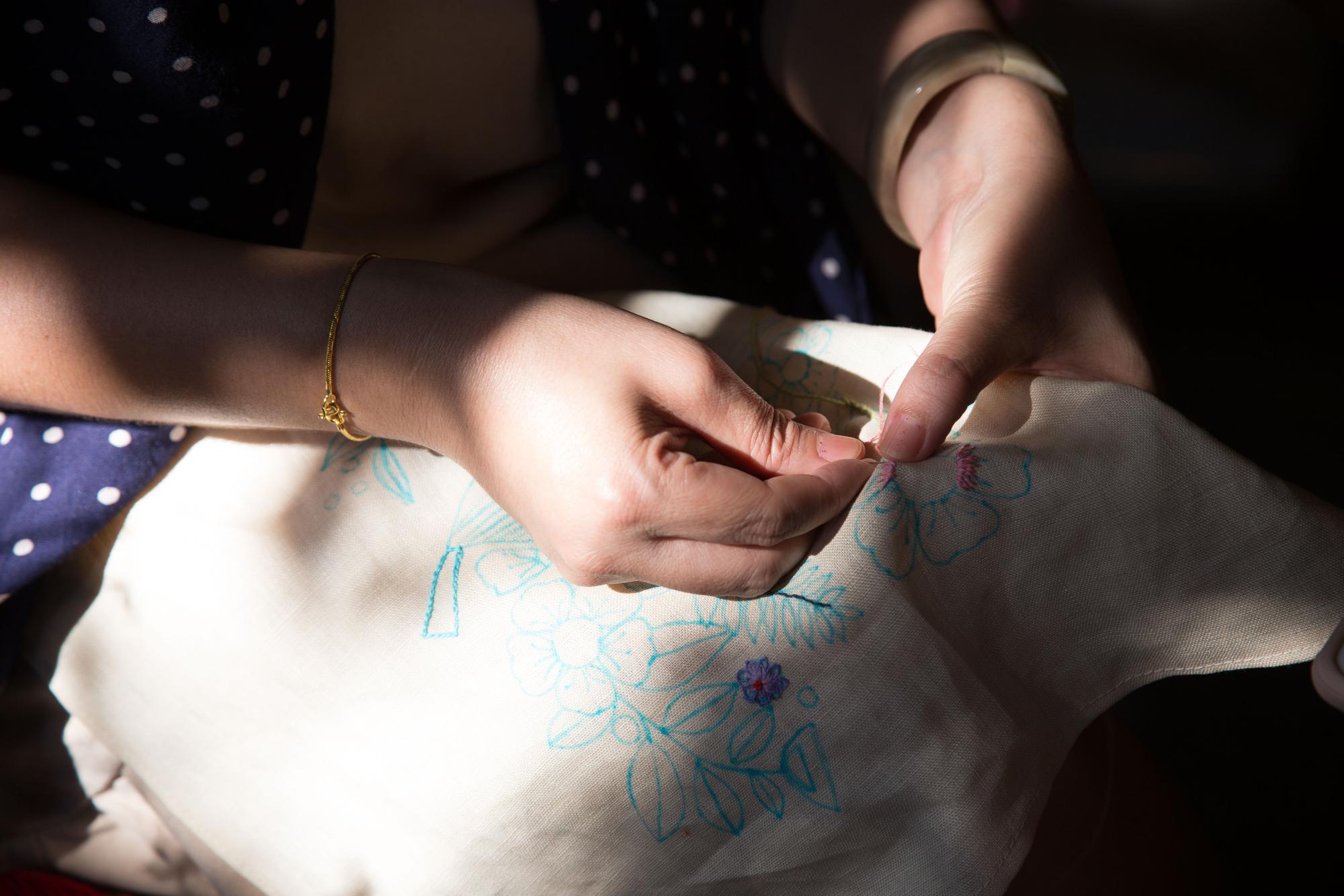 Artist hand finishing embroidered edge